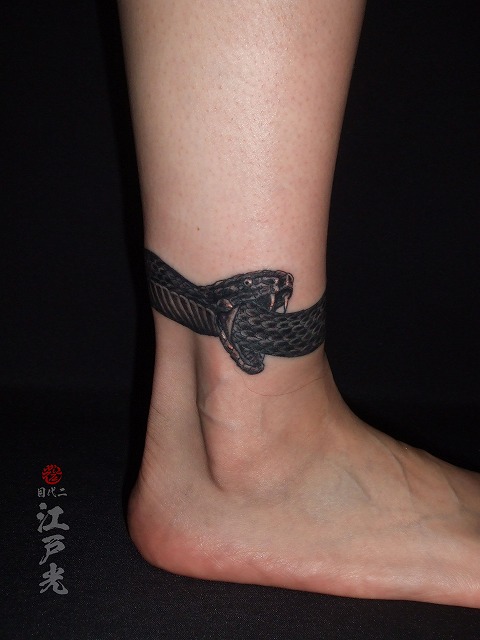 女性の足首に蛇、コブラ、カラス彫りの刺青タトゥー